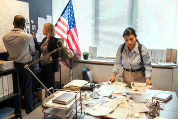 Young female FBI agent looking through criminal profiles of well-known gang members while her...