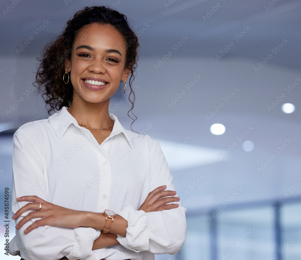 Poster arms crossed because im the boss. shot of a young businesswoman standing with her arms crossed in an