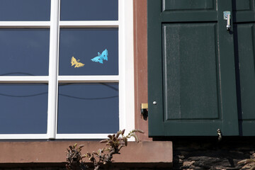 gelber und blauer schmetterling aus papier an einer fensterscheibe