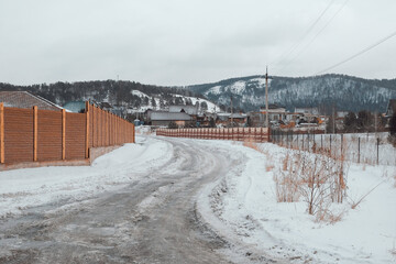 Obraz premium March in the village of Mansky, the snow began to melt, wooden cottages