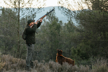 Man with rifle hunting in woods with dog