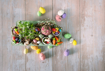 easter bunny, colorful eggs, sweets, candies, marmalade carrots in box on rustic wooden table. Easter Holiday concept. Decoration for festive spring season. top view	