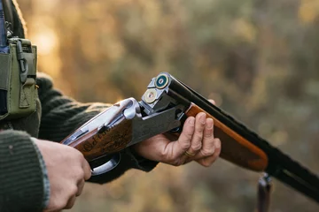 Poster Man loading cartridges in gun for hunting in forest © Jordi Mora