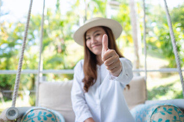 A young woman making and showing thumbs up hand sign