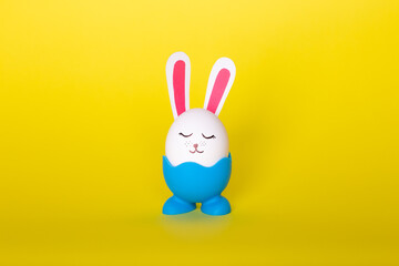 White egg with bunny ears and face. Yellow background