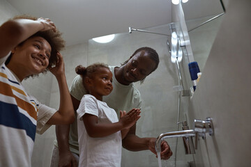 Black family of dad, daughter and son wash faces
