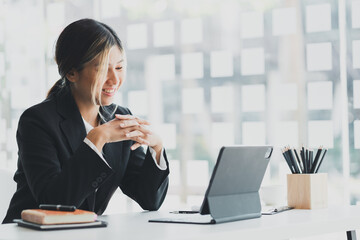 A beautiful Asian businesswoman sitting in her private office, she is checking company financial documents, she is a female executive of a startup company. Concept of financial management.