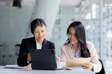 Atmosphere in the office of a startup company, two female employees are discussing, brainstorming ideas to working on summaries and marketing plans to increase sales and prepare reports to managers.