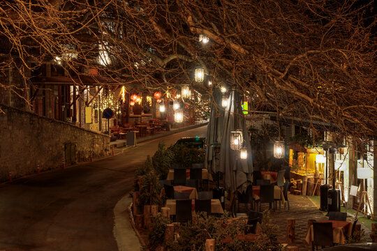 Outdoors cafe and Greek tavern seating area on an empty night street.