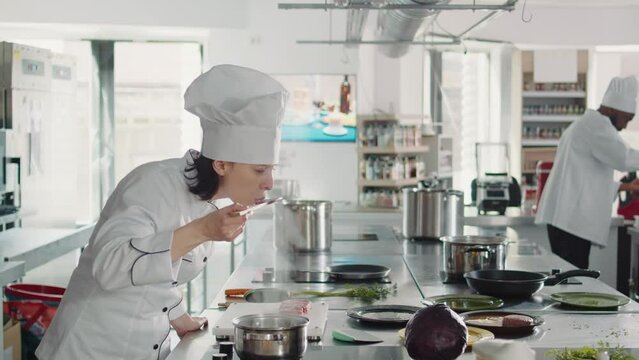 Woman working as cook testing bad soup for gourmet dish, making mistake in preparing culinary recipe. Authentic chef doing taste test with sauce, cooking in professional gastronomy kitchen.