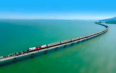 Fototapeta na wymiar Aerial view of Travel train parked on a floating railway bridge over the clear water of lake in Pa Sak Jolasid dam with blue sky at Lopburi, amazing Thailand.
