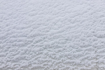 Beautiful winter background with snowy ground. Natural snow texture. Wind sculpted patterns on snow surface