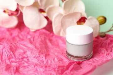 Green light cream in crystal jar with orchid flower on pink paper