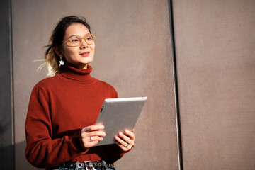 Pretty smiling asian woman holding digital tablet.