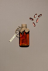 Glass bottle with algae oil and few capsules on brown paper