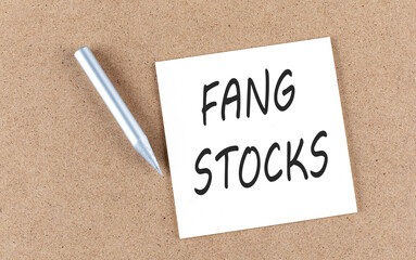 FANG STOCKS text on sticky note on a cork board with pencil ,