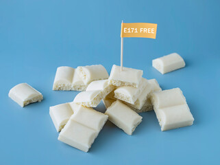 Heap of white chocolate cubes with the sign of a dangerous additive e171 on a blue background