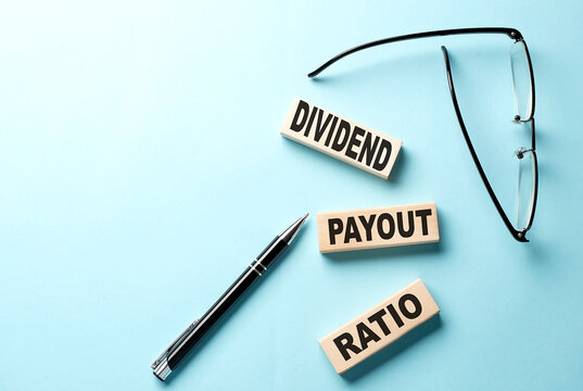 Text DIVIDEND PAYOUT RATIO concept on wooden block on the blue background