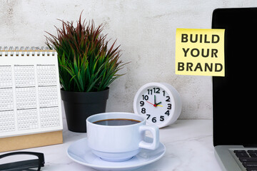 Build your brand typed on yellow paper stick on top of computer screen.