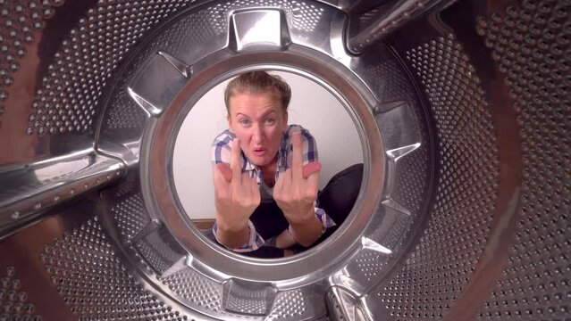 young woman screams swears and shows indecent gestures, fuck you, view from inside washing machine. She cries and screams in hysterics and panic. There's no stopping her. Frustrated with routine work.