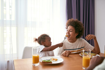 Obraz na płótnie Canvas Little girl feeding her brother egg from fork