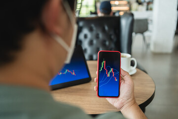 Man holding phone and looking at candlestick chart suitable for Stock market forex or cryptography trading financial investment graphs Finance Economy trends Trading Stock Concept