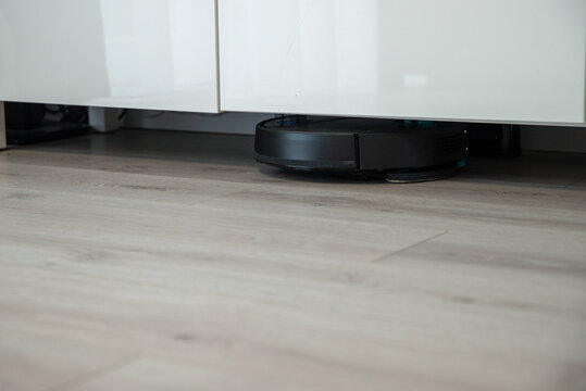 Robot vacuum cleaner is cleaning floor, under the furniture