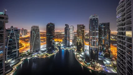 Poster Tall residential buildings at JLT aerial night to day timelapse, part of the Dubai multi commodities centre mixed-use district. © neiezhmakov