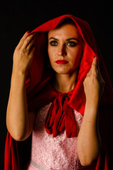 beautiful woman red cloak with red flowers roses in studio. Woman Red Riding Hood. Dramatic and fantastic shooting,fashionable toning. Like a princess