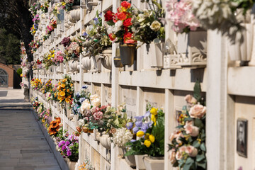 Italian wall cemetery with tombstones and artificial flowers on a sunny summer day in Venice,...