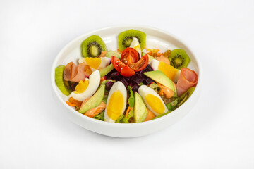 Fresh salad made with fresh kiwi avocado eggs mixed vegetables on white bowl