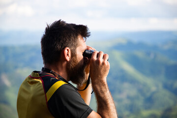 man using binoculars while trekking in nature