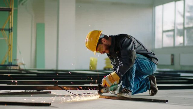 In a large building construction the hard working man cutting some metals with the disc welding machine at construction site