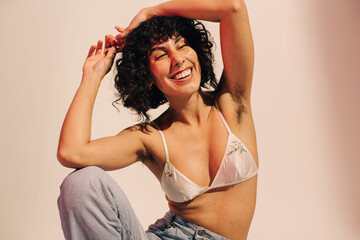 Unshaven young woman smiling cheerfully while wearing a bra - obrazy, fototapety, plakaty