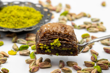 Obraz na płótnie Canvas Chocolate baklava with pistachio on a white background. Traditional Turkish cuisine delicacies. Local name is fıstıklı çikolatalı baklava
