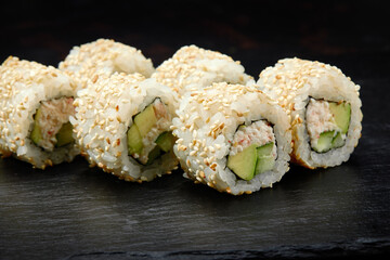 Traditional delicious fresh sushi roll set on a black background. Sushi roll with rice, cream cheese, avocado, salmon, sesame. Philadelphia. Sushi menu. Japanese kitchen, restaurant.