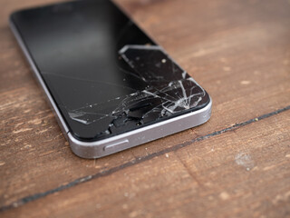 Smartphone with a broken screen on a wooden table - 495896716