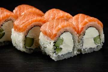 Philadelphia roll sushi with tuna, cucumber and cream cheese on black background for menu. Japanese food