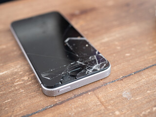 Smartphone with a broken screen on a wooden table - 495896743