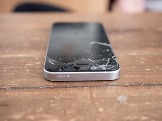 Smartphone with a broken screen on a wooden table - 495896747