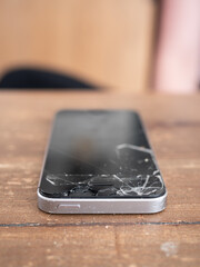 Smartphone with a broken screen on a wooden table - 495896765