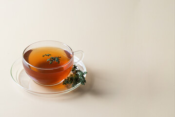Herbal thyme in glass cup with thyme banch on beige background. Natural relax beverage. Copy space