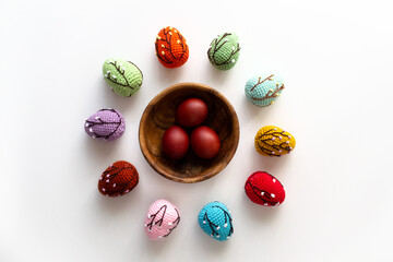Naklejka na ściany i meble Easter card with colored crocheted eggs and red Easter eggs in a wooden plate. Easter crafts