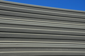 noise barrier made of metal perforated sheet metal slats. gray and silver protective fencing...