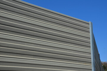 noise barrier made of metal perforated sheet metal slats. gray and silver protective fencing...