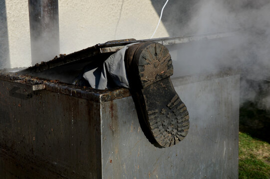 repair piping with hot water steam in hatch of device. only shoes and feet look out of tank. smoke rolls in winds which rolls fog, dust. stainless steel kitchen equipment washes inside men, film, army