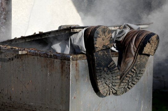 repair piping with hot water steam in hatch of device. only shoes and feet look out of tank. smoke rolls in winds which rolls fog, dust. stainless steel kitchen equipment washes inside men, film, army