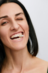 Pretty young woman with a pill in her teeth, isolated against white background. Taking supplement pill into her Mouth. Healthy Eating And Diet Nutrition Concepts.