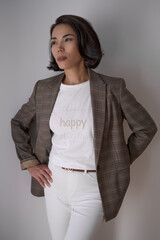 Portrait of a brunette asian woman with hairstyling and make up, wearing t shirt, blazer and white...