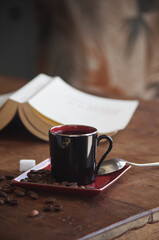 Tasse de café , carré de sucre et grains de café éparpillés sur une table avec livre en...